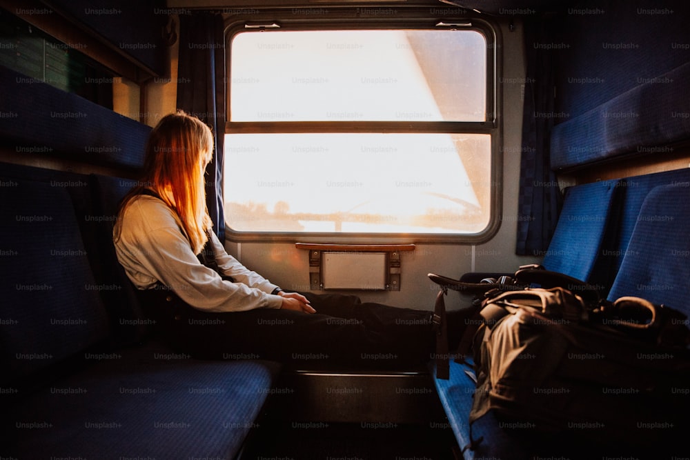 電車に座って窓の外を眺める女性