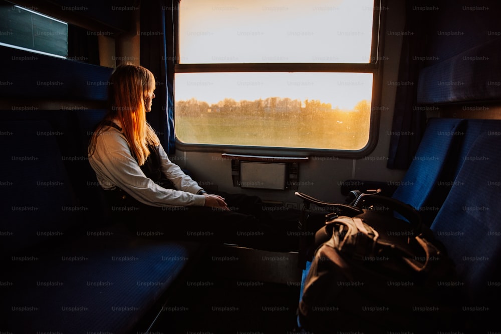 電車に座って窓の外を眺める女性