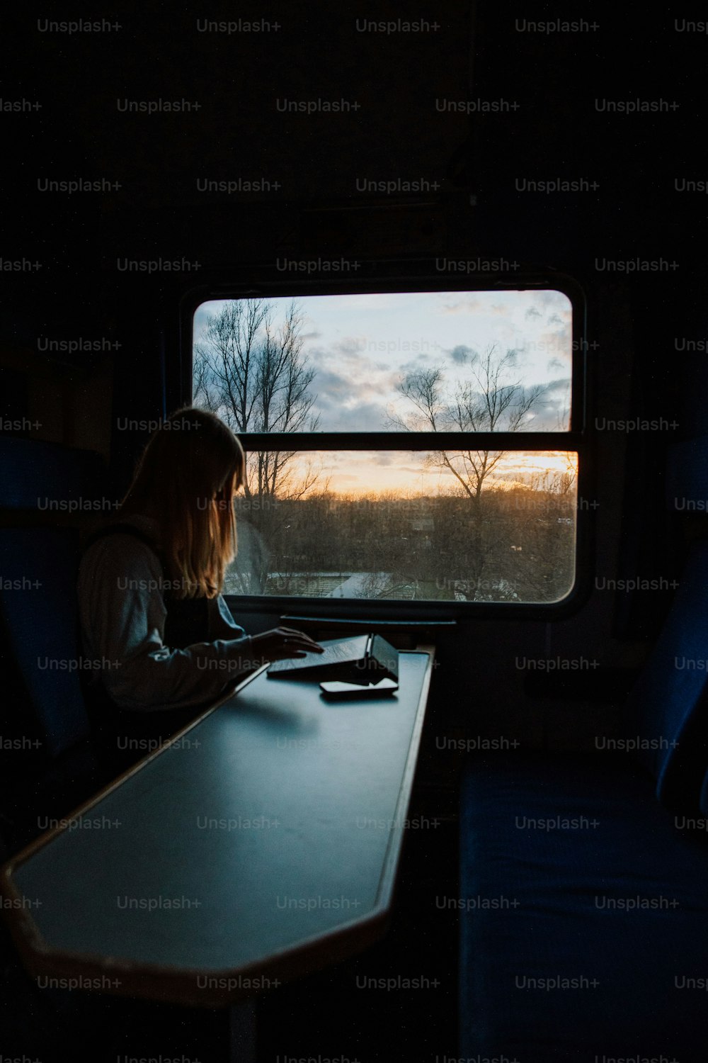 Una mujer sentada en una mesa mirando por una ventana