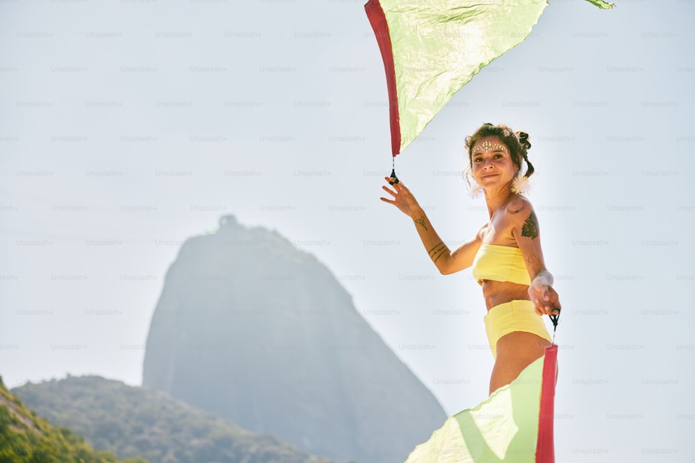 a woman holding a kite in front of a mountain