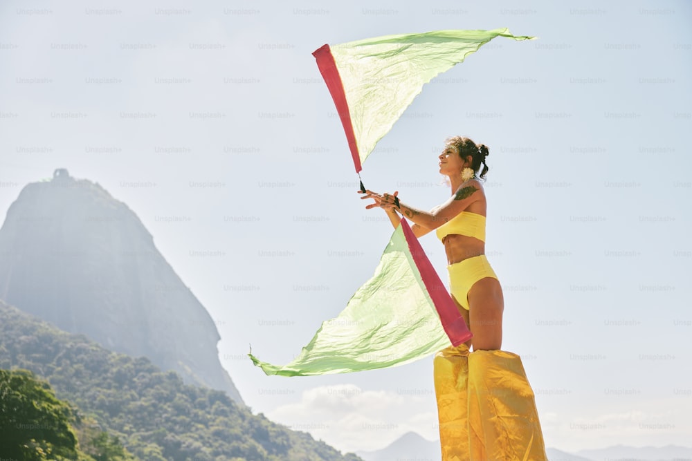 Une femme en bikini jaune tenant un cerf-volant vert et rouge