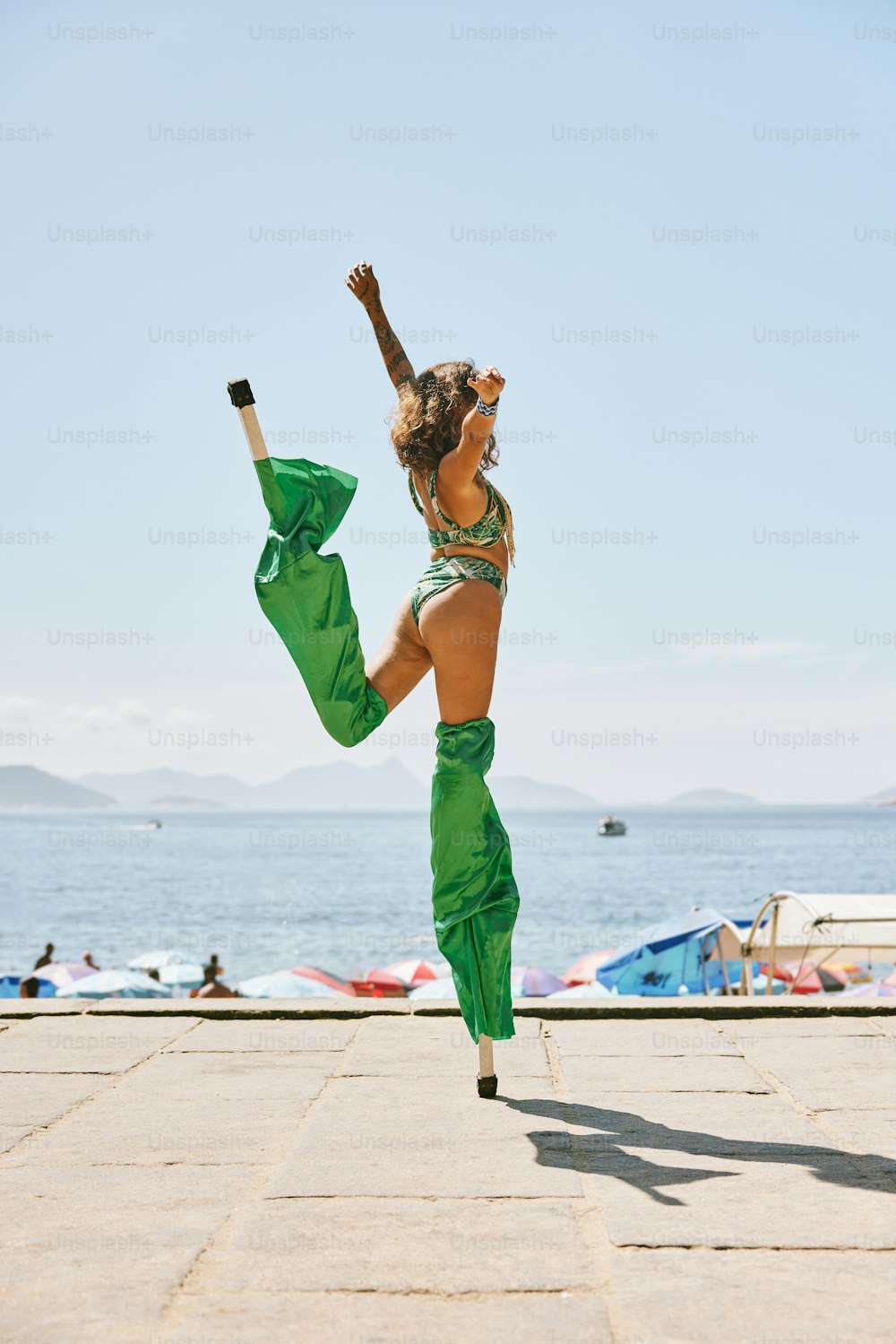a woman in a bikini top and green pants doing a handstand
