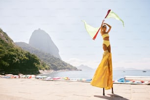 a woman in a yellow dress holding a yellow scarf