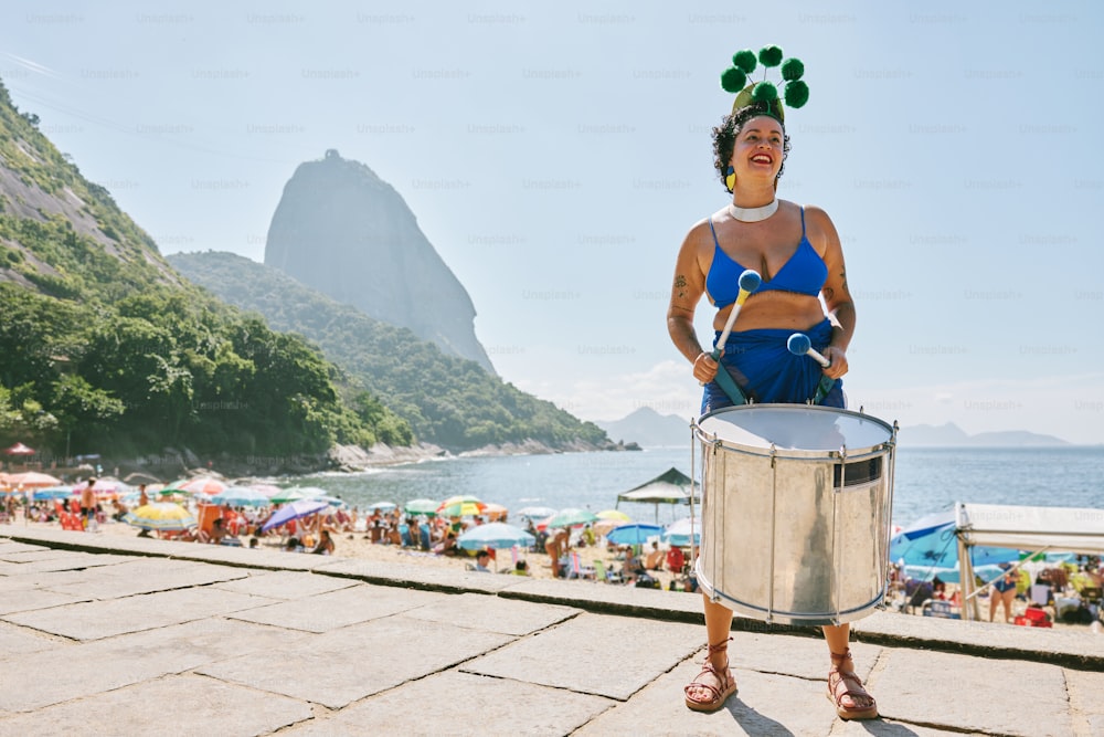 Una mujer en bikini azul sosteniendo un tambor de metal