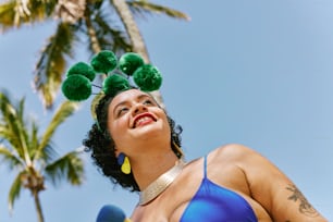 a woman in a blue bikini with green pom poms on her head
