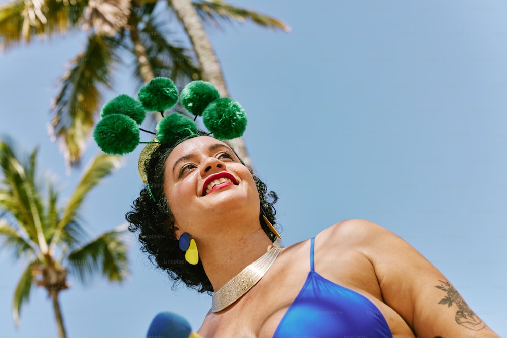 a woman in a blue bikini with green pom poms on her head