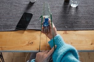 une personne tient une bouteille d’eau sur une table