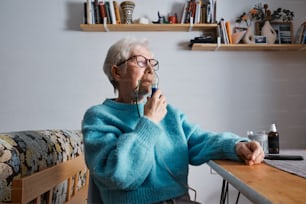 노트북이 있는 테이블에 앉아 있는 노인 여성