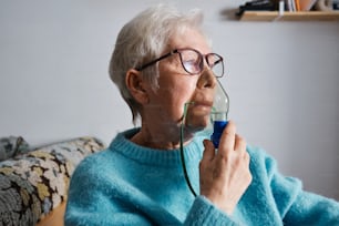 an elderly woman wearing glasses holding a blue object in her hand