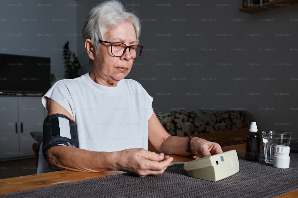 eine ältere Frau, die mit einem Verband am Arm an einem Tisch sitzt