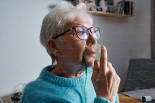 Eine ältere Frau, die eine Brille trägt und ein Handy ans Ohr hält
