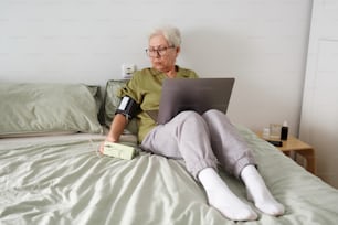 una persona seduta su un letto con un computer portatile