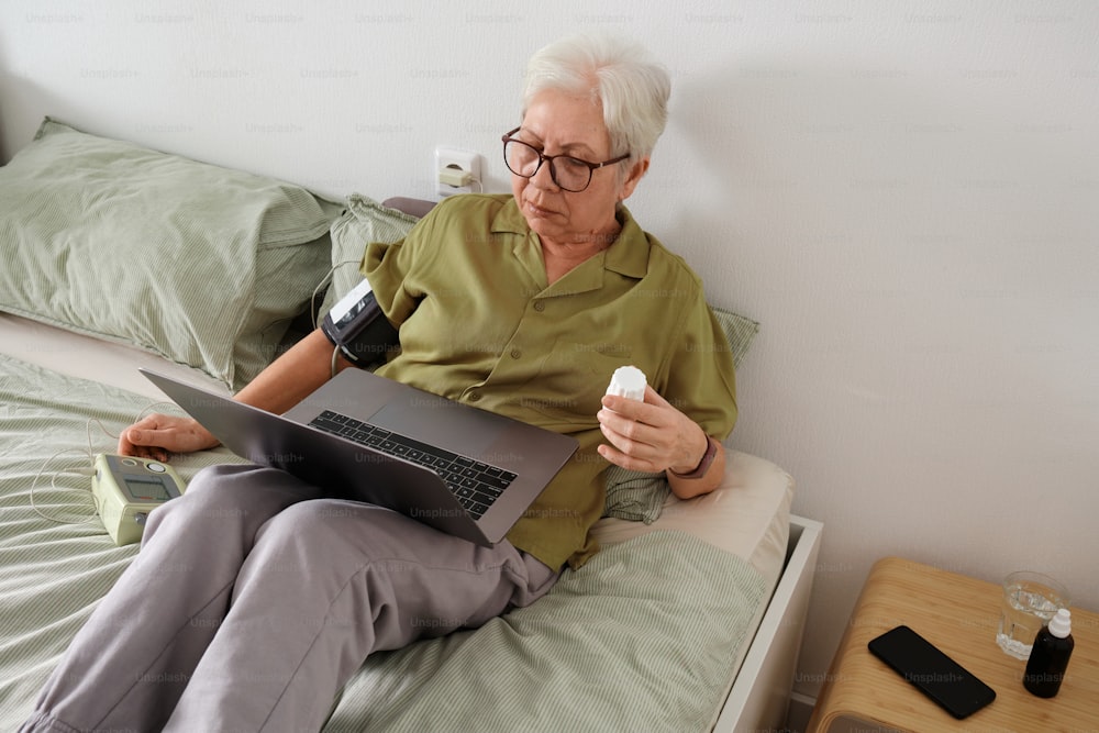 una persona seduta su un letto con un computer portatile