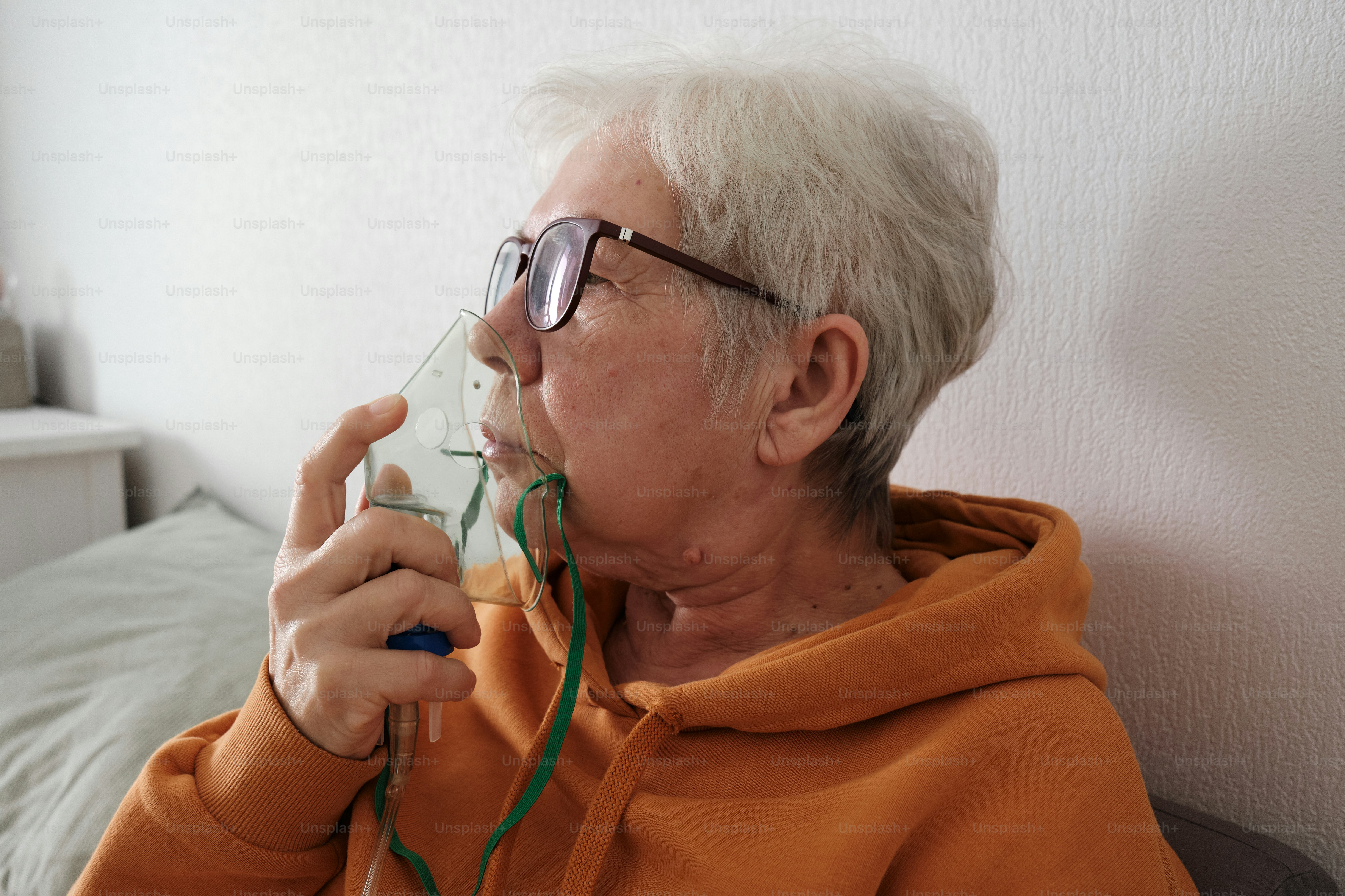 elderly woman at home breathing through an oxygen mask