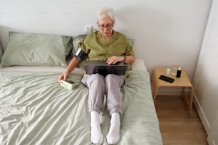 a person sitting on a bed with a laptop
