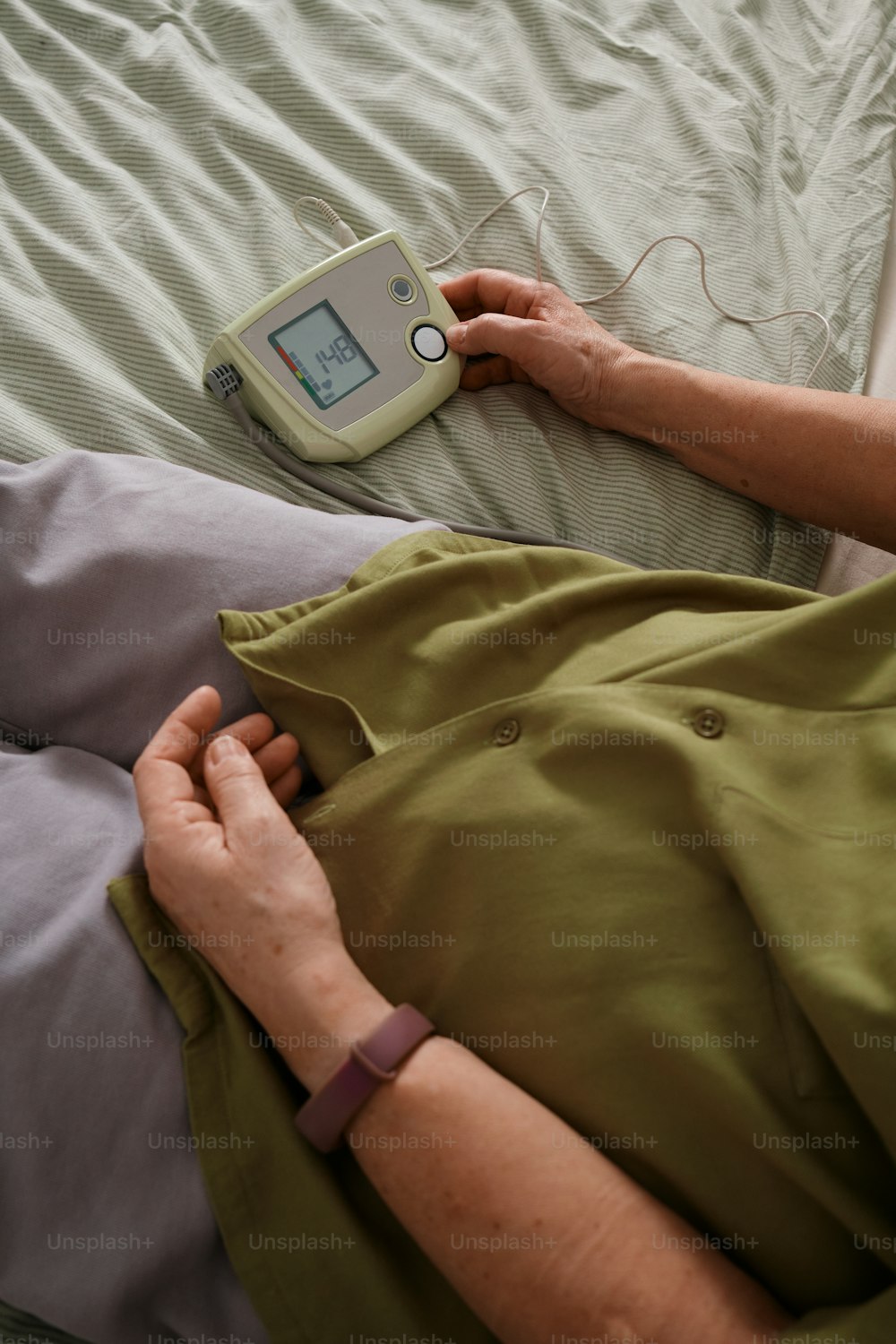 a woman laying in bed with a thermometer on her arm