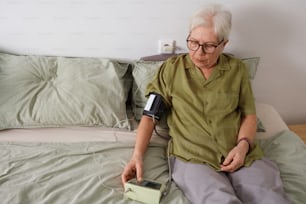 uma mulher sentada em uma cama segurando um dispositivo