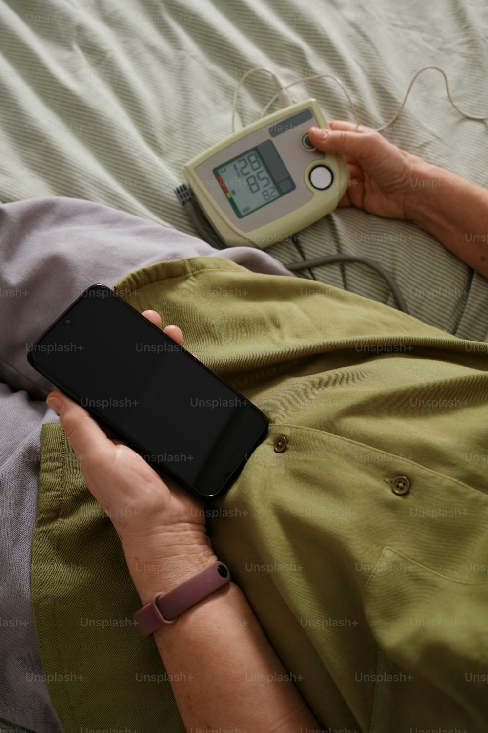 uma pessoa deitada em uma cama com um telefone celular