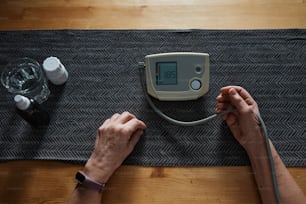 una persona che utilizza un misuratore di pressione sanguigna su un tavolo