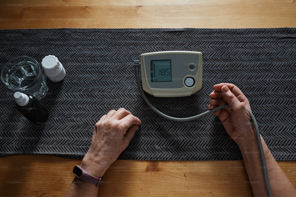 una persona che utilizza un misuratore di pressione sanguigna su un tavolo