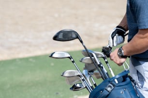 a man holding a golf club and a bag of golf clubs