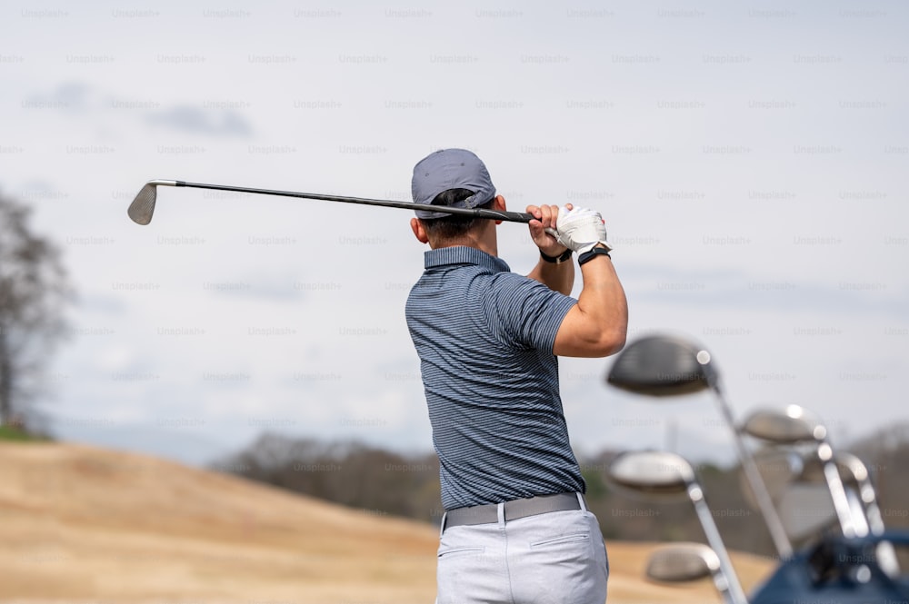 um homem balançando um taco de golfe em um campo de golfe
