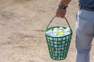 a person holding a basket of golf balls
