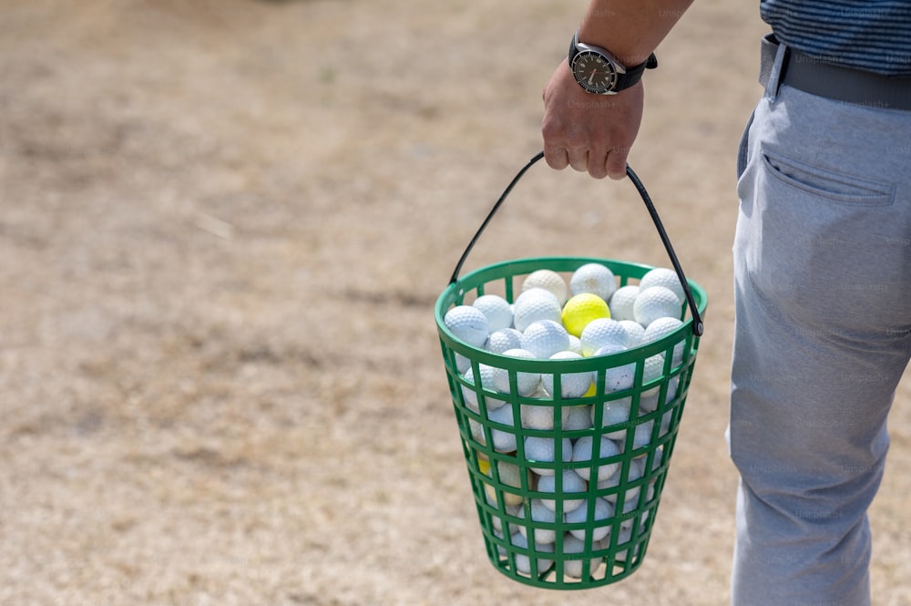 una persona che tiene un cesto di palline da golf