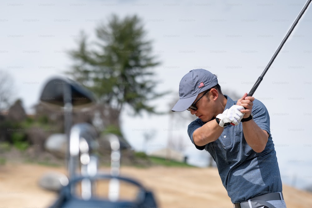 um homem balançando um taco de golfe em um campo de golfe