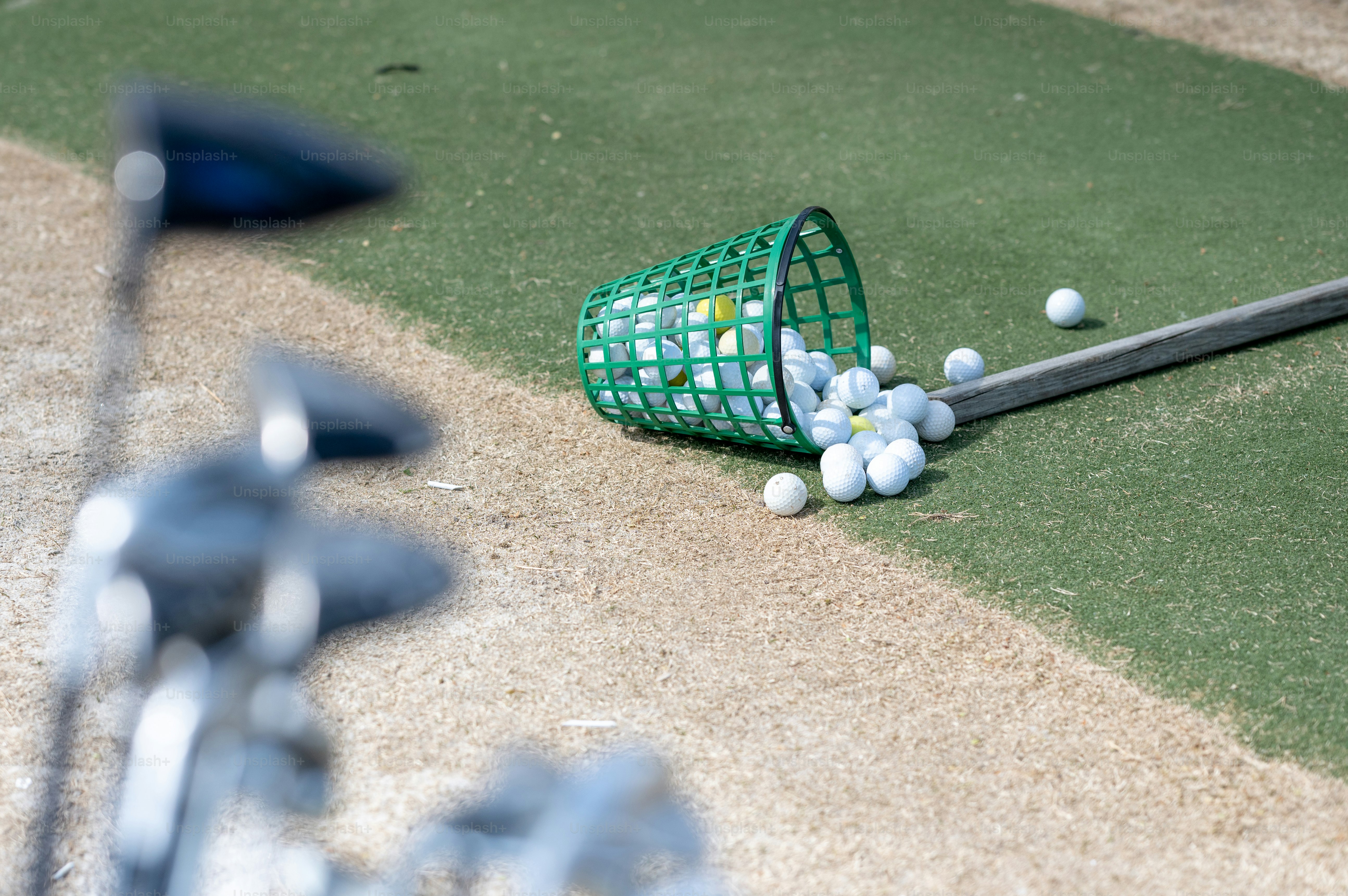 Ein grüner Korb mit Golfbällen auf dem Boden