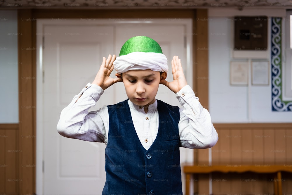 a young boy wearing a green and white hat