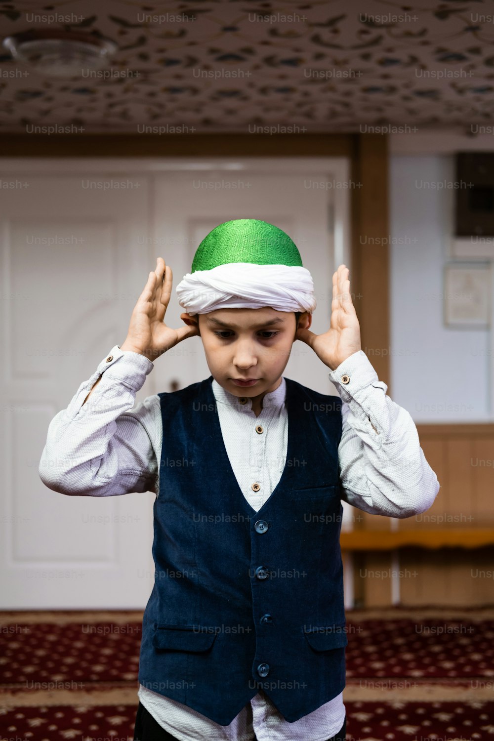 a young boy wearing a green and white hat