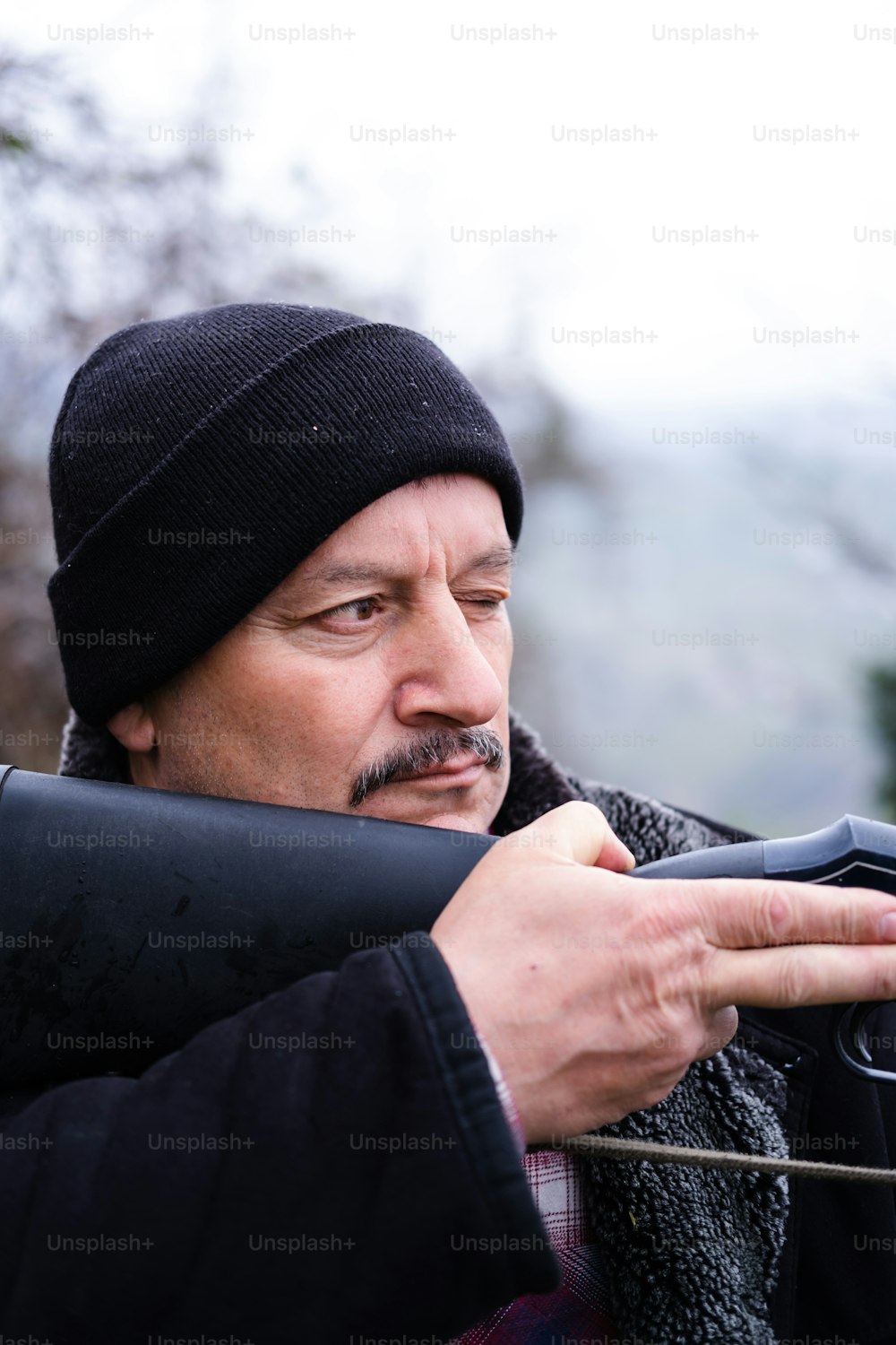 um homem de chapéu preto segurando um telefone celular