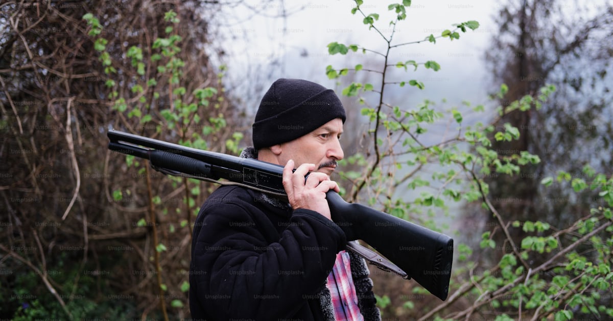 A man holding a rifle and smoking a cigarette photo – Hunting Image on ...