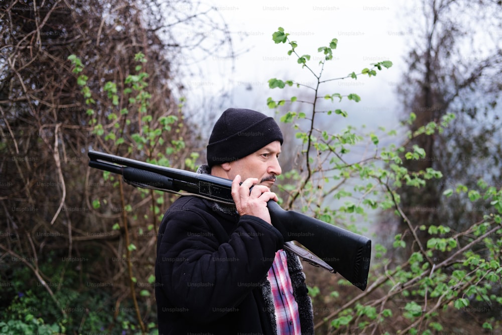 a man holding a rifle and smoking a cigarette