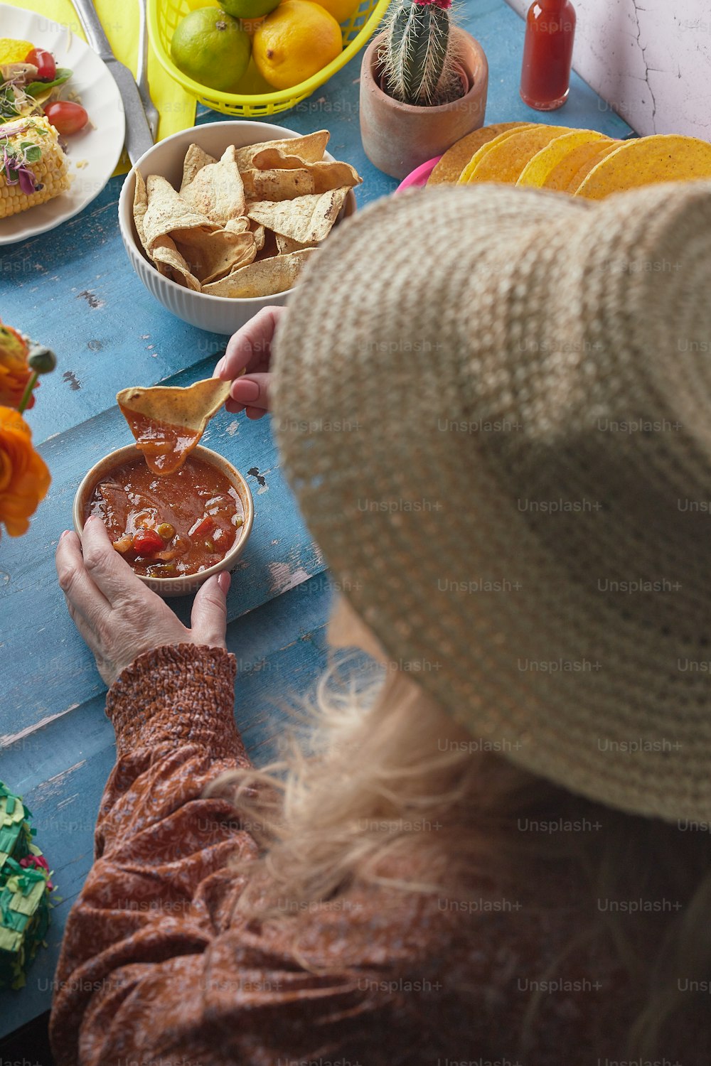 Una donna con un cappello tiene in mano una ciotola di salsa