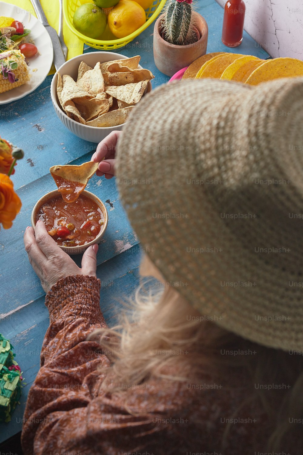 a woman in a hat is holding a bowl of salsa