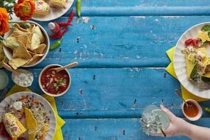 a person holding a glass of water near plates of food