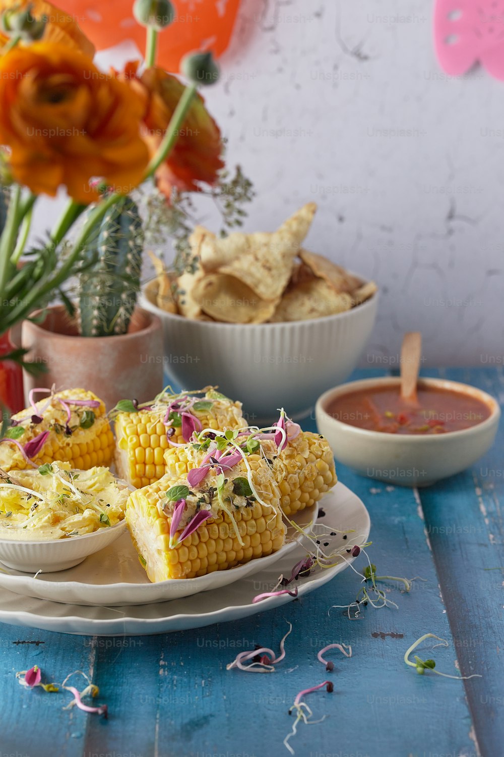 a plate of corn on the cob next to a bowl of salsa