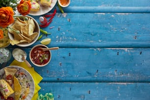 a table topped with plates of food and bowls of salsa