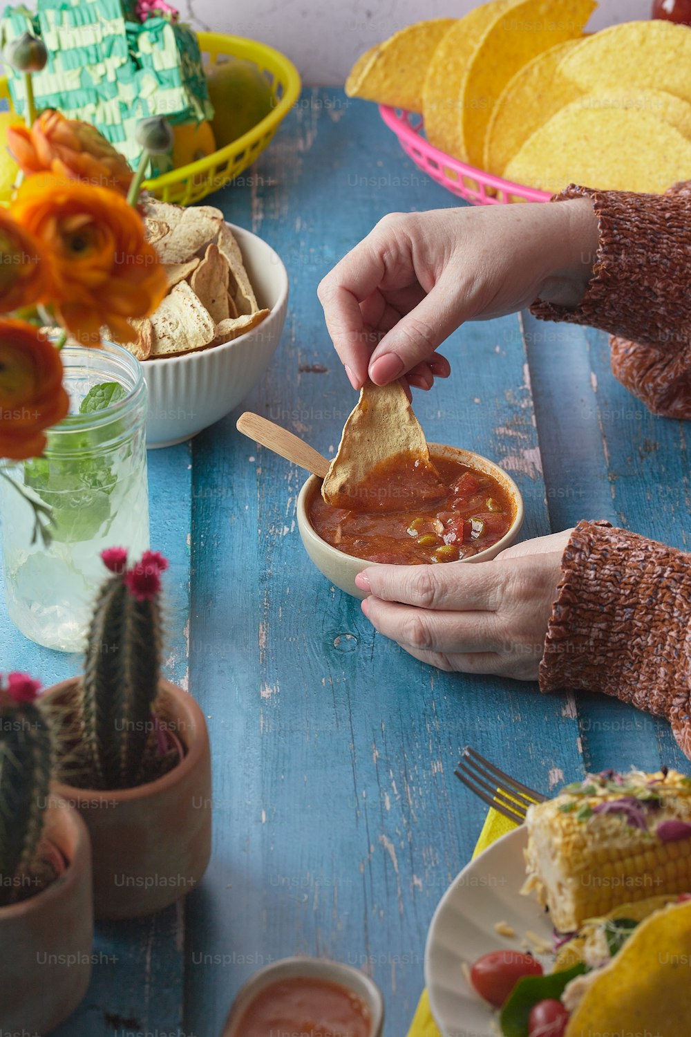 a person dipping a tortilla into a bowl of salsa