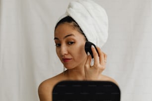 Eine Frau mit einem Handtuch auf dem Kopf, die ein Handy benutzt