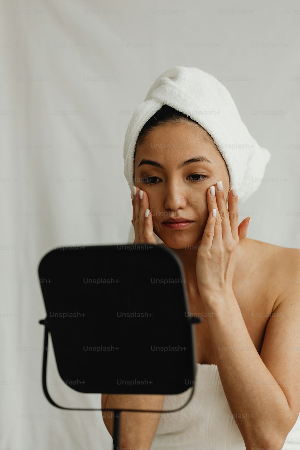 a woman with a towel on her head looking at a mirror