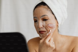 a woman with a towel on her head using a face mask