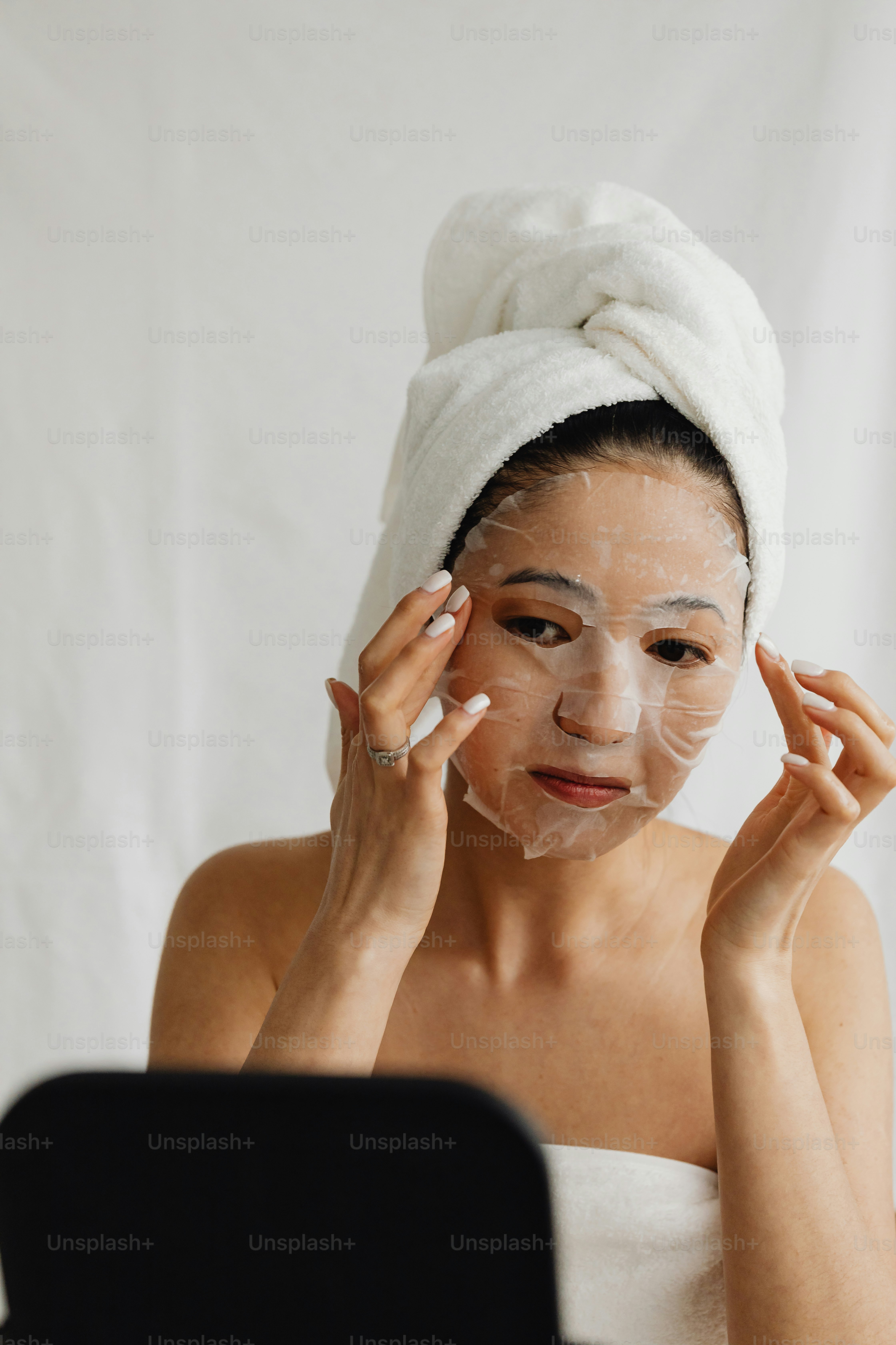 頭にタオルをかぶり、フェイスマスクをした女性