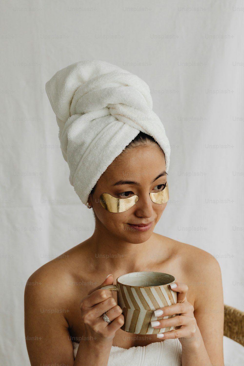 eine Frau mit einem Handtuch auf dem Kopf, die eine Tasse hält