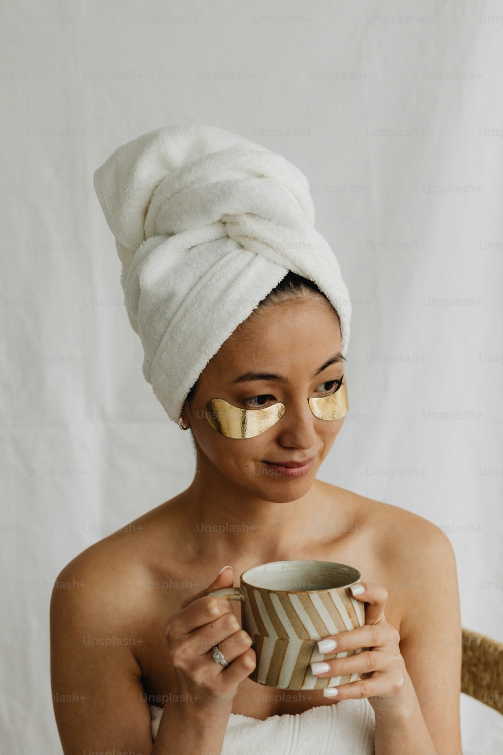 a woman with a towel on her head holding a cup