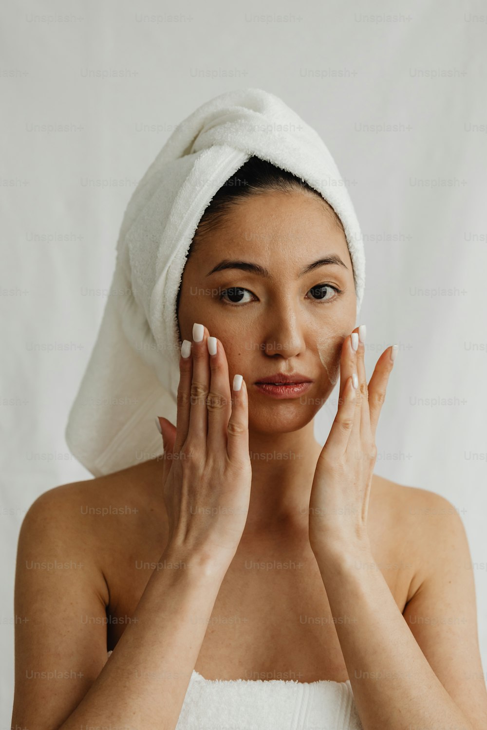 a woman with a towel on her head holding her hands to her face