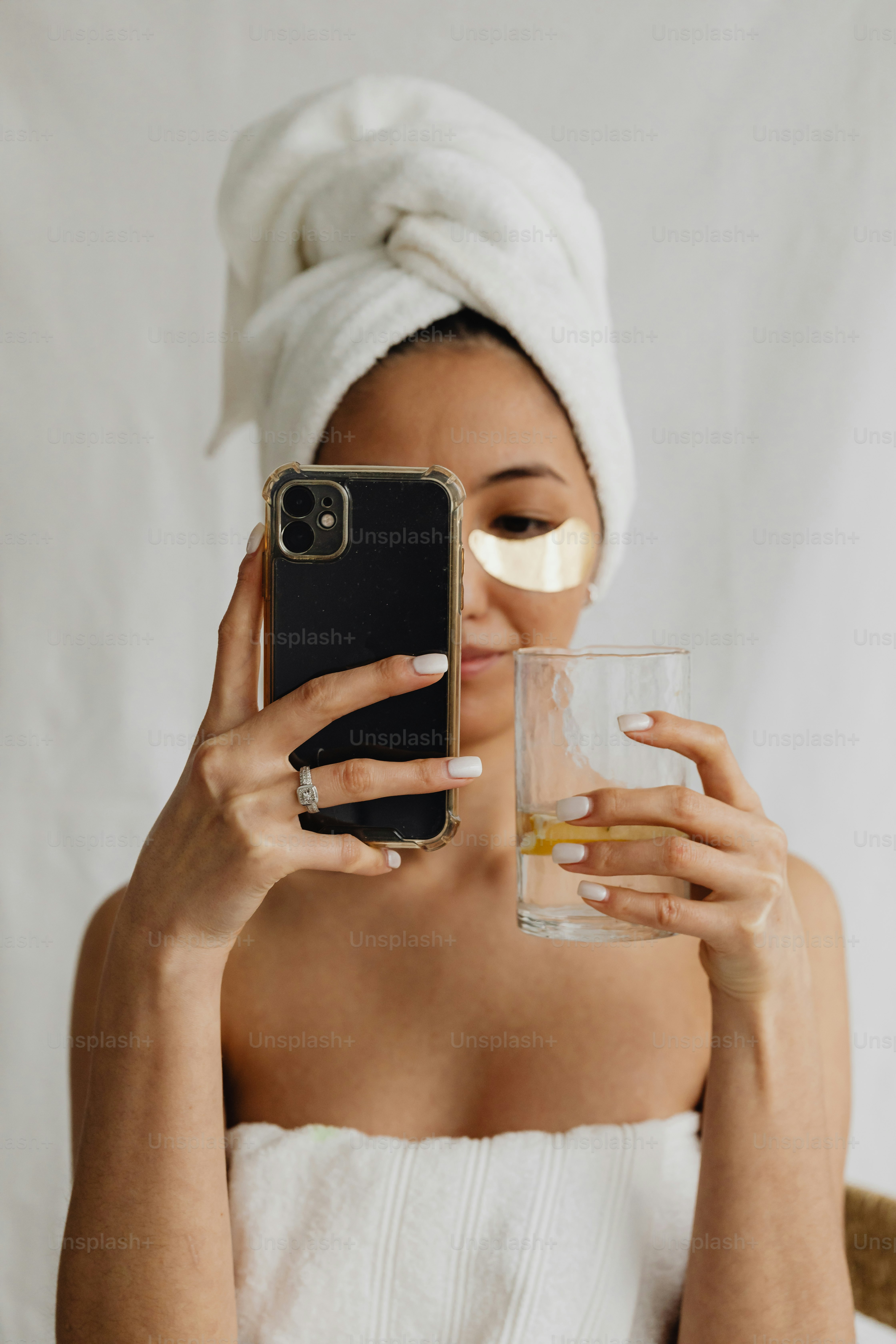 携帯電話を持つ頭にタオルをかぶった女性