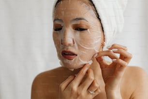 Eine Frau mit einem Handtuch auf dem Kopf rasiert sich das Gesicht